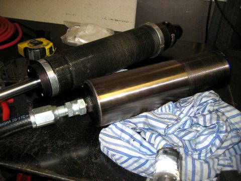 1996 Ford Bronco - Close-up of two shock absorbers and a hydraulic hose on a workbench.