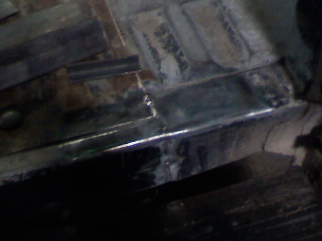 Close-up of metal framing and floor panels, possibly from a vehicle under repair