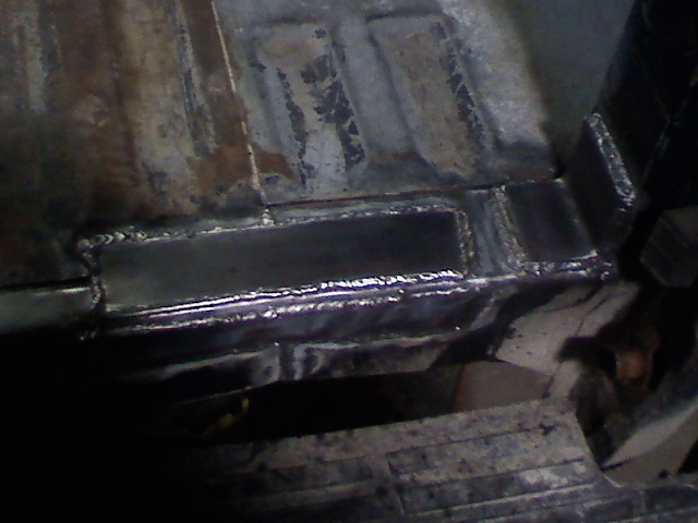 Fresh weld beads on a repaired steel frame section of a truck undercarriage