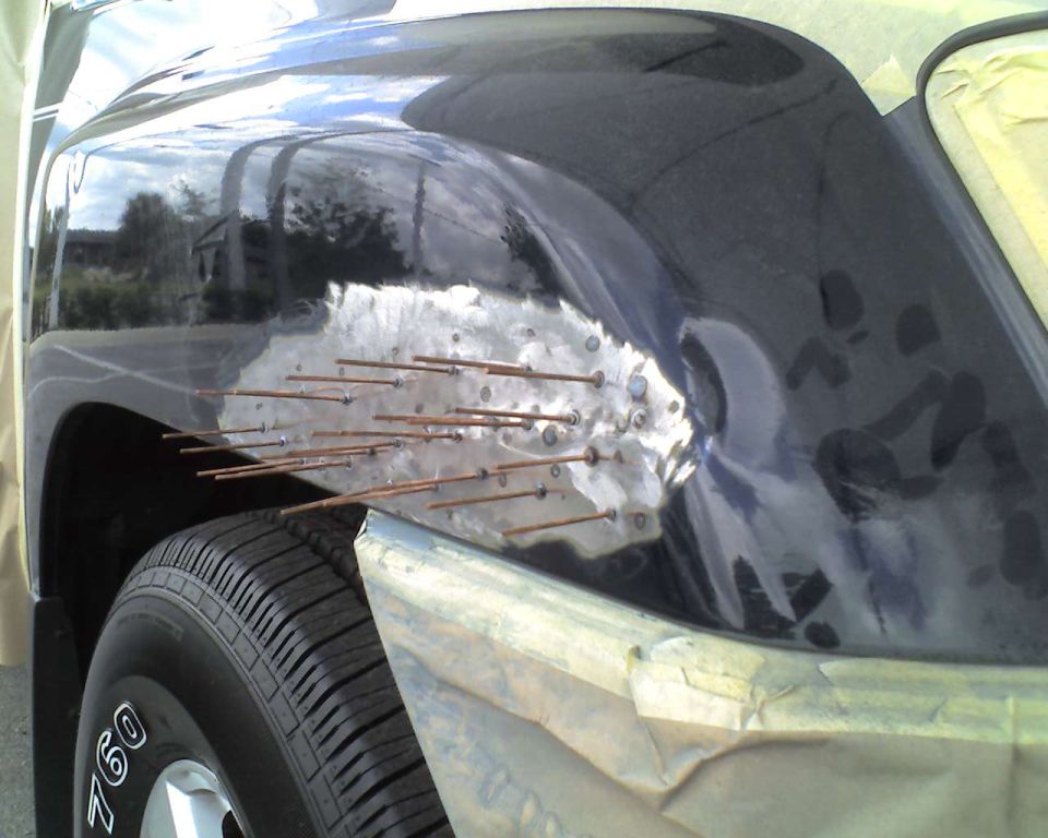 Vehicle fender being repaired with small metal rods welded to it