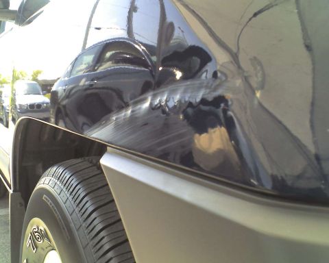 1993 Ford C-350 (Centurion Conversions) - This dark SUV shows extensive damage to its rear side panel and door, with reflections of other vehicles visible.
