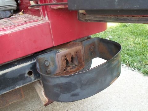 1988 Jeep YJ - The rear bumper mount of a red Jeep YJ shows extensive rust and a protective black metal guard.