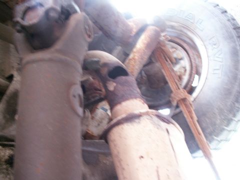 1988 Jeep YJ - Close-up view of the undercarriage, showing the driveshaft, exhaust components, and a tire.