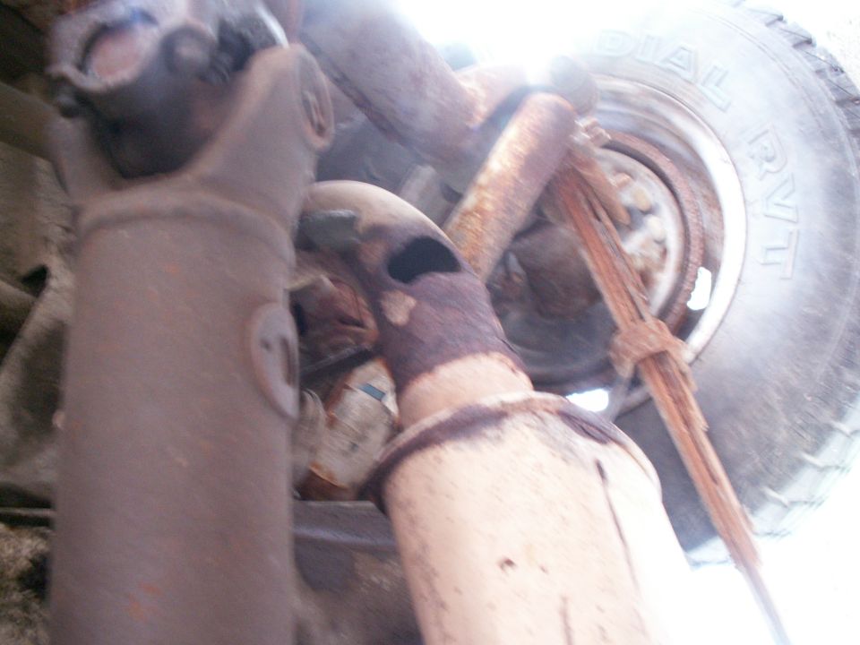 Underside view of vehicle driveshaft and exhaust system, with a tire visible
