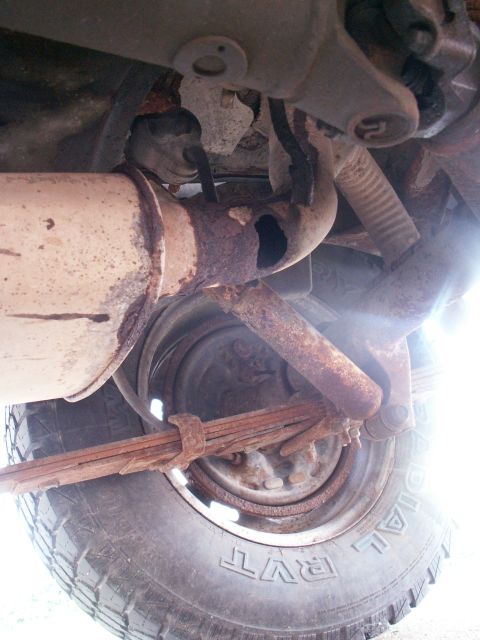 1988 Jeep YJ - Close-up of a vehicle's rusty exhaust system and suspension components.