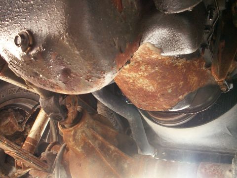 1988 Jeep YJ - Close-up of heavily rusted underside components, including suspension and drivetrain parts, with a Supermotors.net watermark.