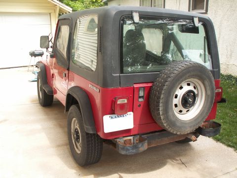 1988 Jeep YJ - Rear view of a red Jeep Wrangler parked in a driveway next to a garage.