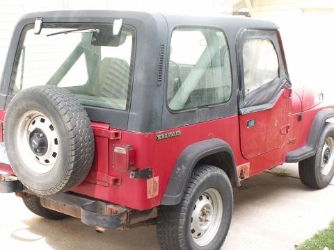 1988 Jeep YJ - Rear 3/4 view of a red 1988 Jeep YJ Wrangler showing its spare tire and some body rust.