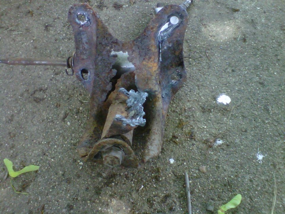 rusted suspension part with visible welds and a bolt