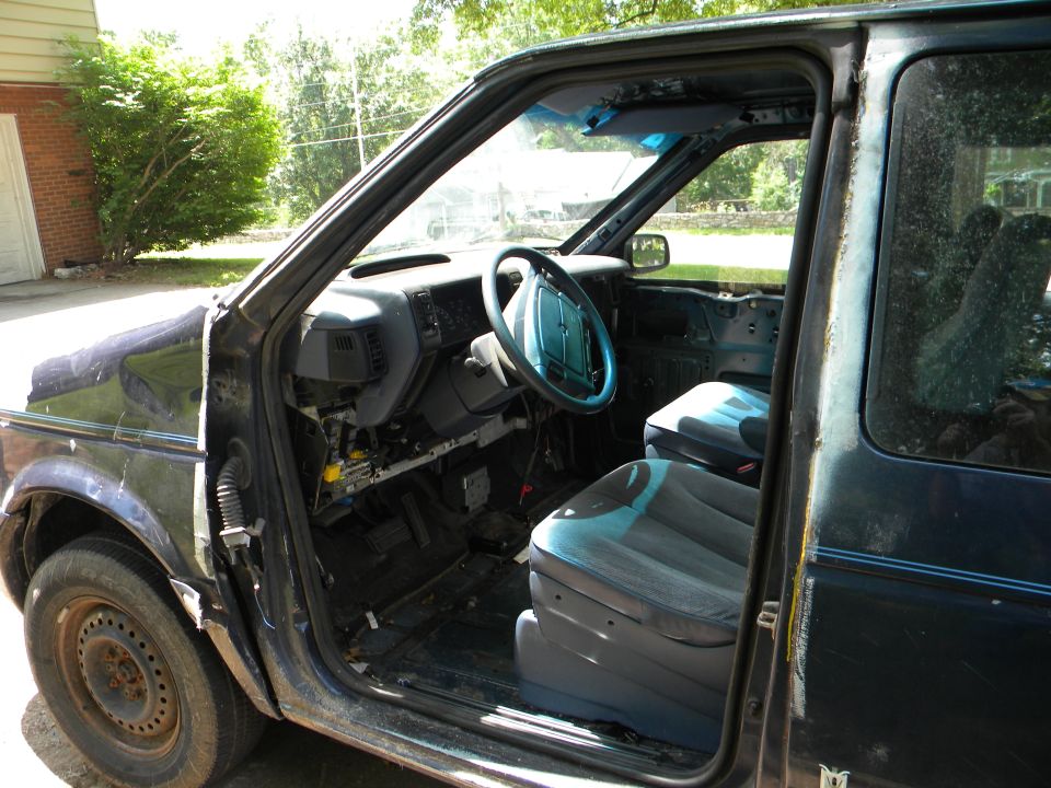 van interior, dashboard, steering wheel, and front seats visible. Door is open