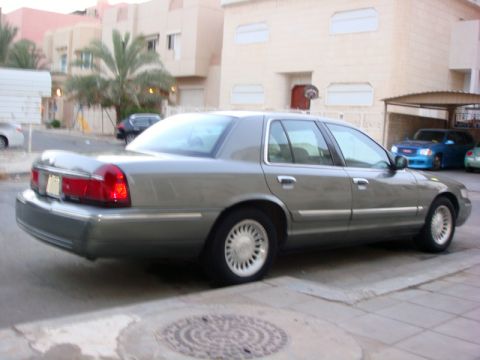 2001 Mercury Grand Marquis - A gray sedan is parked on a street with buildings and other vehicles visible in the background.