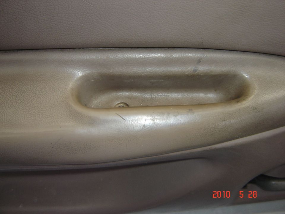 Tan plastic door handle with a visible screw and scratches