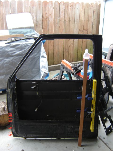 1993 Ford Bronco - A detached car door is being worked on, with tools and a bottle of liquid nearby.