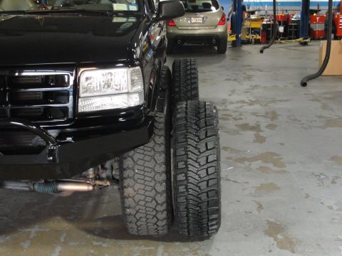 1995 Ford Bronco - Comparison of two different tire sizes on a black SUV in a garage setting.