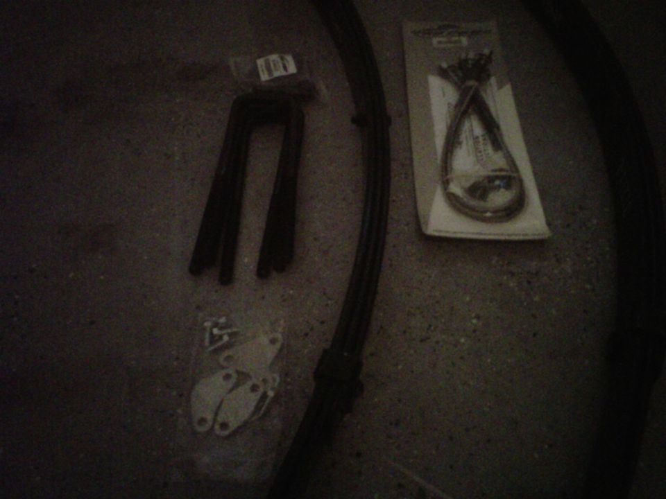 U-shaped metal parts in plastic packaging, a bundle of cables in packaging, and small metal brackets with screws on a dark surface