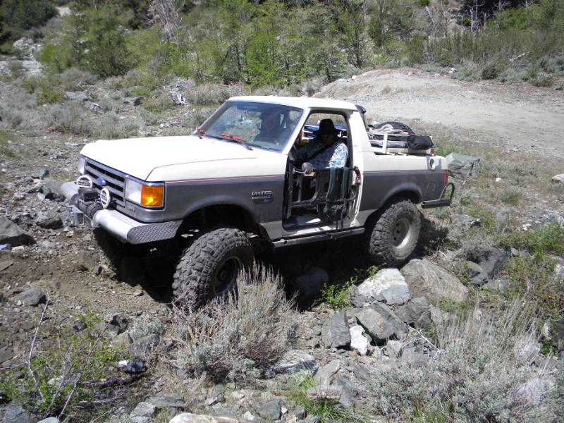 1991 Ford Bronco driving over rocks on a dirt trail