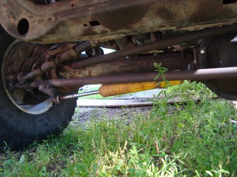 1999 Ford F-150 - Undercarriage view of a 1999 Ford F-150, highlighting the steering linkage and a yellow shock absorber.