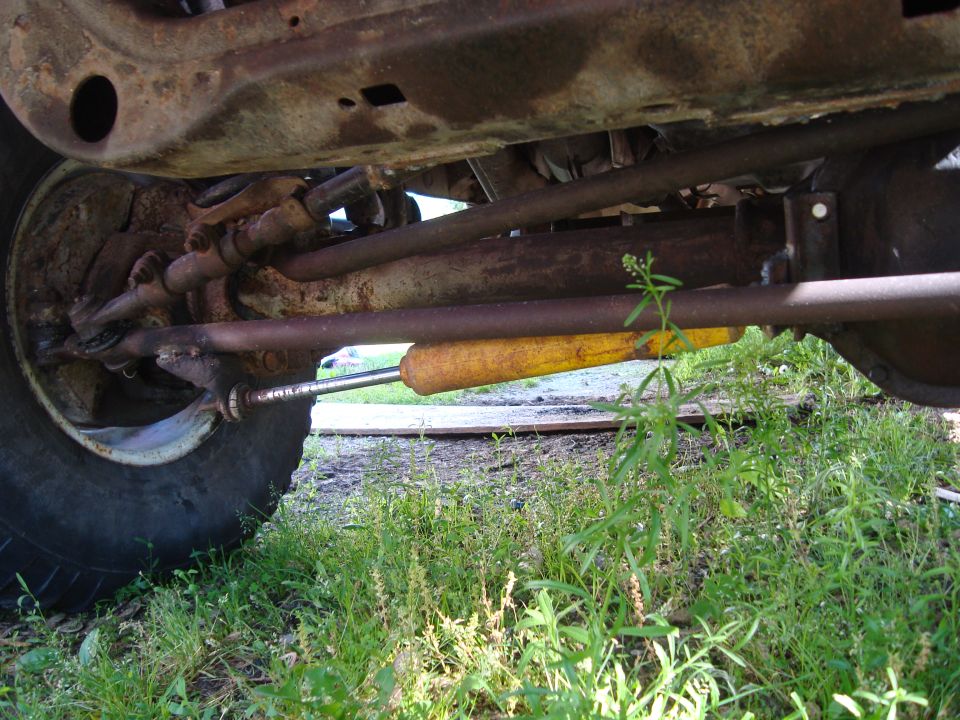 Undercarriage of 1999 Ford F-150 showing steering linkage and yellow shock absorber