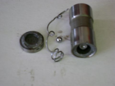 1972 Ford Ranchero - A hydraulic valve lifter disassembled on a light workbench surface, with the outer body standing on end beside its plunger cap, coil check-…