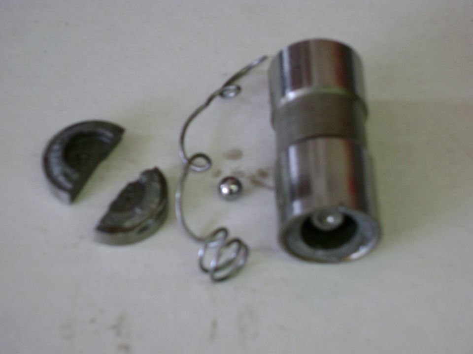 Engine lifter components including a roller, spring, and two broken pieces on a white surface