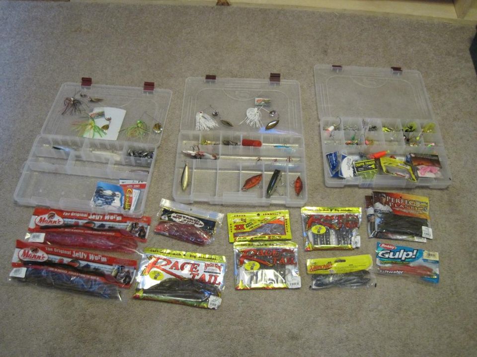 Three open tackle boxes filled with fishing lures and accessories, with additional fishing lure packages on the floor