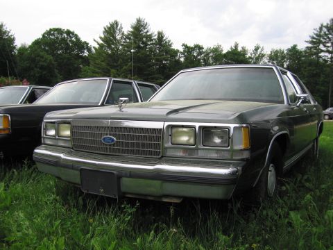 1991 Ford LTD Crown Victoria - Front view of a dark green Ford Crown Victoria parked in grass next to another car.