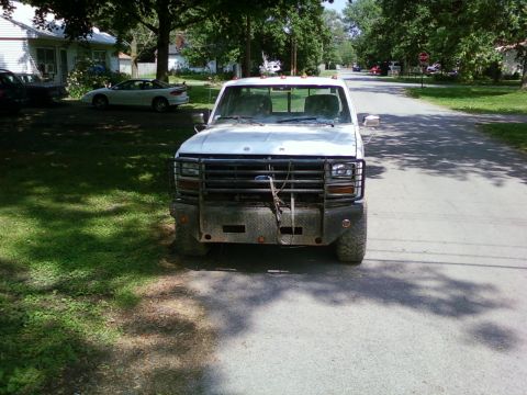 1989 Ford Bronco - This white pickup truck features a heavy-duty brush guard and a diamond plate bumper, suggesting it is built for off-road or work use.