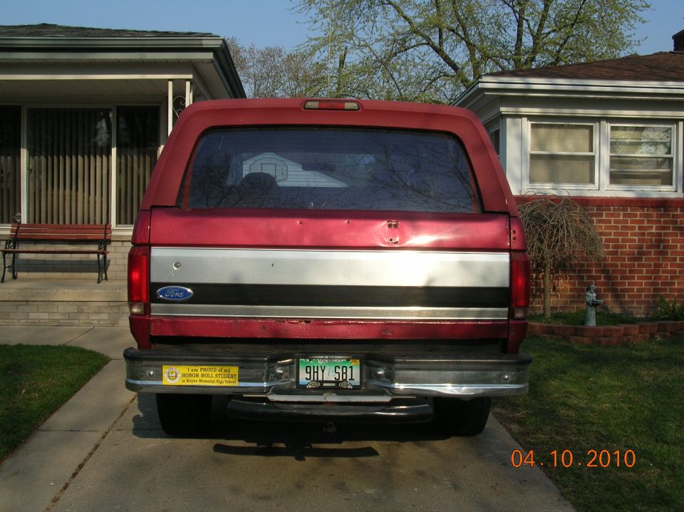 Red Ford Bronco rear view, silver stripe on tailgate, yellow bumper sticker