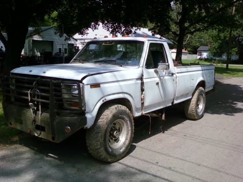 1989 Ford Bronco - This white pickup truck, likely from the 1980s, features a prominent bull bar and aftermarket wheels.