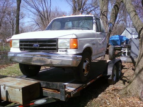 1989 Ford Bronco - White Ford F-Series truck being transported on a trailer.