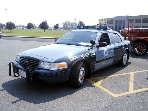 1998 Ford Crown Victoria - A 1998 Ford Crown Victoria police car is parked on asphalt with yellow markings.