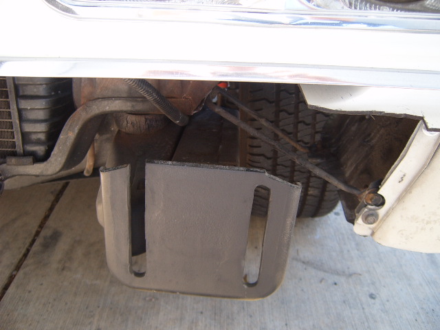 Underside of a vehicle showing a spare tire, some metal bracing, and a black protective cover