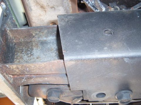 1973 Ford Ranchero - Close-up view of rusted vehicle frame components and a black metal cover plate, showing signs of wear.