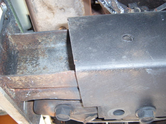 Vehicle frame components with rust and a black metal cover plate