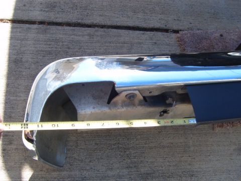 1973 Ford Ranchero - A chrome bumper is measured with a tape measure against a concrete surface.