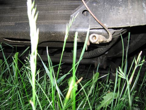 1991 Ford LTD Crown Victoria - Close-up view of a vehicle's front undercarriage, with grass in the foreground.