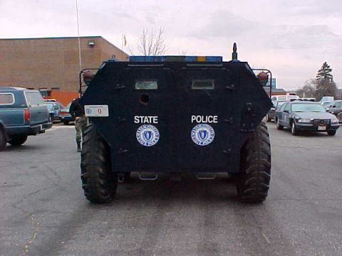 1998 Ford Crown Victoria - An armored vehicle with 'STATE POLICE' markings is parked in a lot with other vehicles visible.