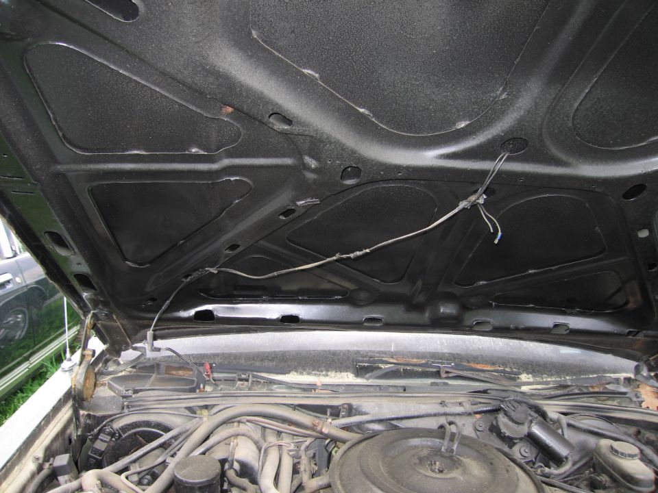Car hood interior with wiring and engine components visible below