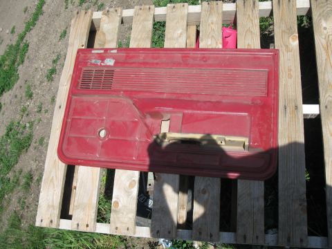 1977 Ford F-250 - This is a red truck door panel, likely from an older model, resting on wooden pallets outdoors.