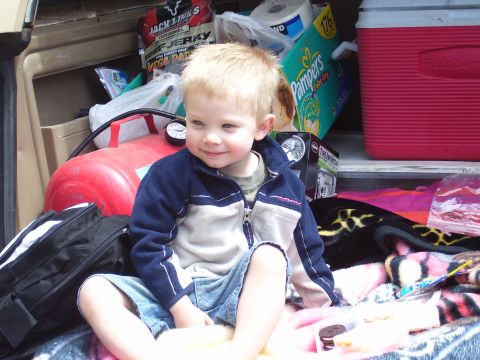1991 Ford Bronco - A young child sits amongst various items in the back of a vehicle.