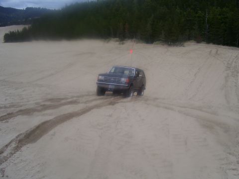 1991 Ford Bronco - Ford Bronco navigates sandy terrain under an overcast sky.