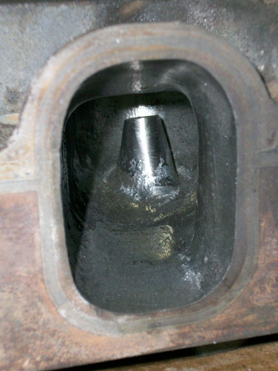 Close-up of an engine cylinder head intake port with a valve guide visible