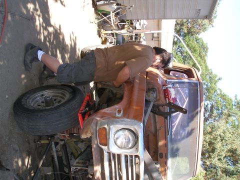1969 Ford F-250 - Man works on the front end of a vintage pickup truck, possibly a 1970s model.