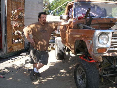 1969 Ford F-250 - Man poses with a vintage pickup truck that appears to be undergoing repairs or modifications.