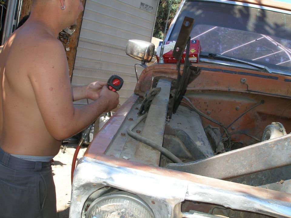 Orange 1967 Ford F-100 truck engine bay with a man holding a tool