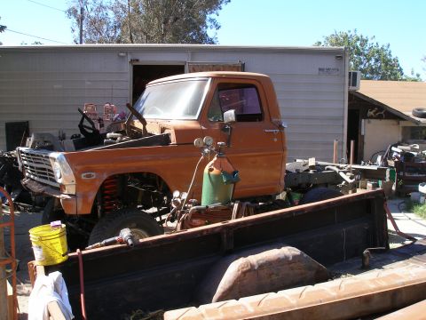 1969 Ford F-250 - This orange Ford F-series truck chassis is missing its hood and engine, with visible front suspension components.