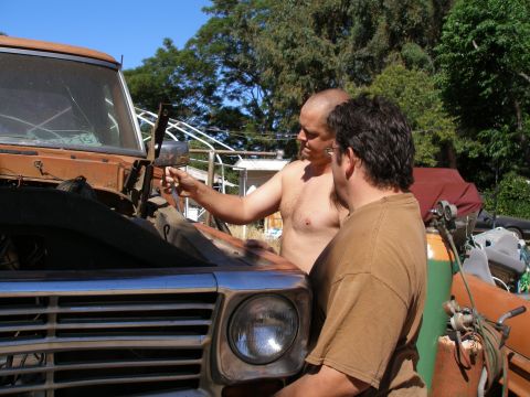 1969 Ford F-250 - Two men examine the engine bay of a weathered orange truck.