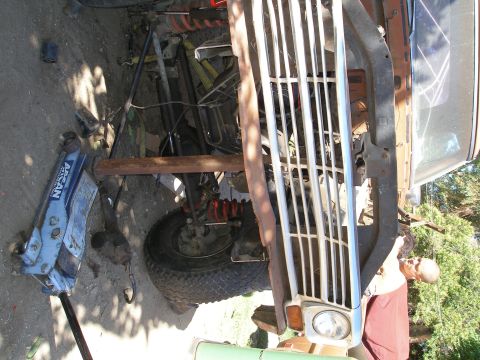 1969 Ford F-250 - Front end of a 1969 Ford F-250 undergoing repairs, with the grille detached and engine bay exposed.