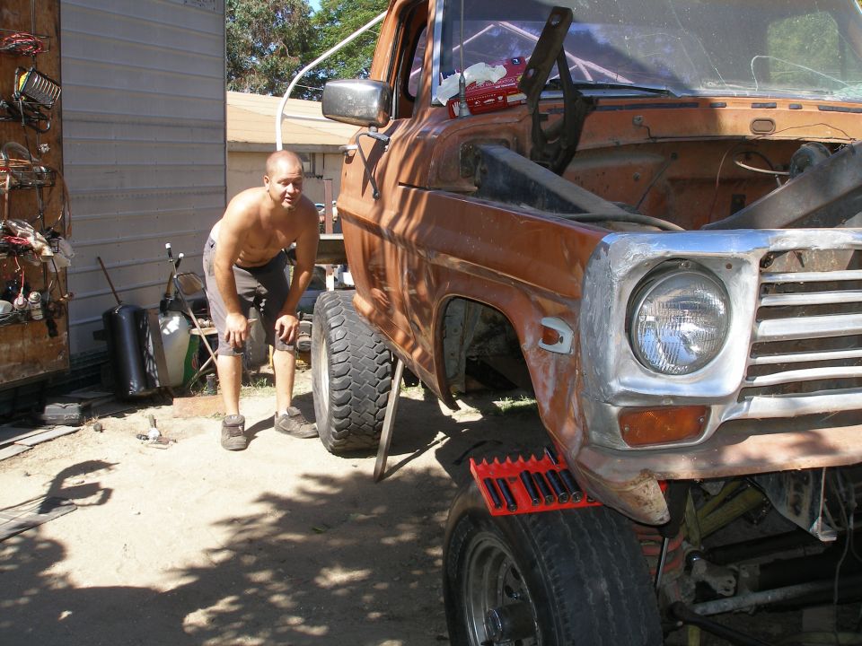 Orange pickup truck front end with hood open, being worked on