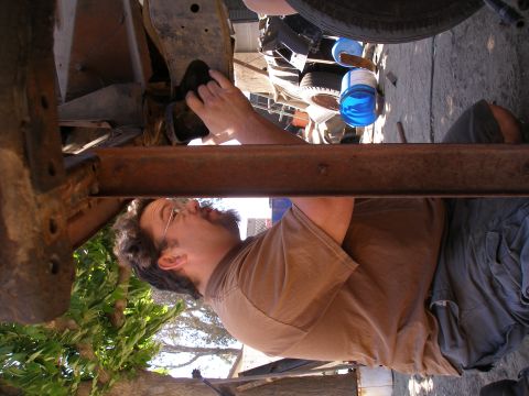 1969 Ford F-250 - A mechanic works on the undercarriage of a vehicle, with a tire visible above.